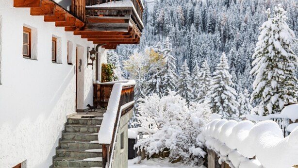 Una escalera de madera que lleva a un balcón con una montaña nevada de fondo.