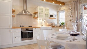 Une cuisine moderne avec des meubles blancs, une hotte en acier inoxydable et un coin repas aménagé pour prendre un repas.
