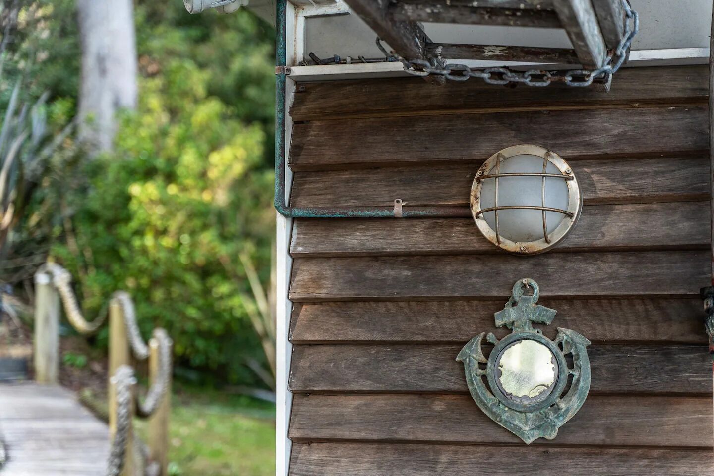 Une façade en bois, agrémentée d’une lanterne en métal et d’un élément décoratif en métal.