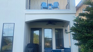 Un bâtiment à deux étages doté d’un balcon, d’un espace extérieur aménagé pour s’asseoir et d’un coin barbecue couvert.