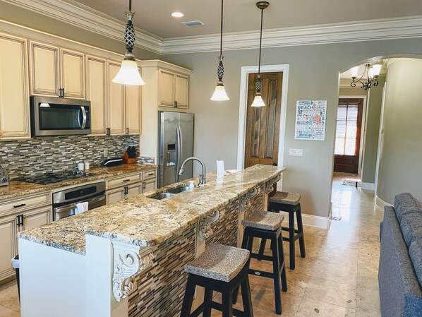 A modern kitchen with granite countertops, stainless steel appliances, and a central island with bar stools.