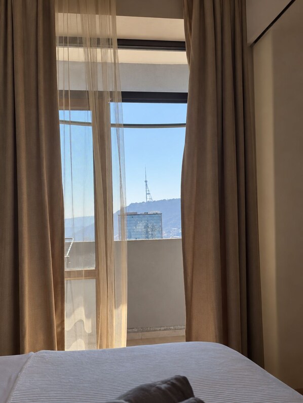 Een hotelkamer met een groot raam, gordijnen en een bed.