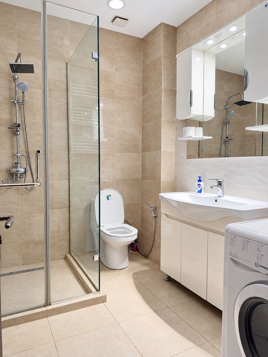 A modern bathroom with a glass shower enclosure, a toilet, a sink, and a washing machine.