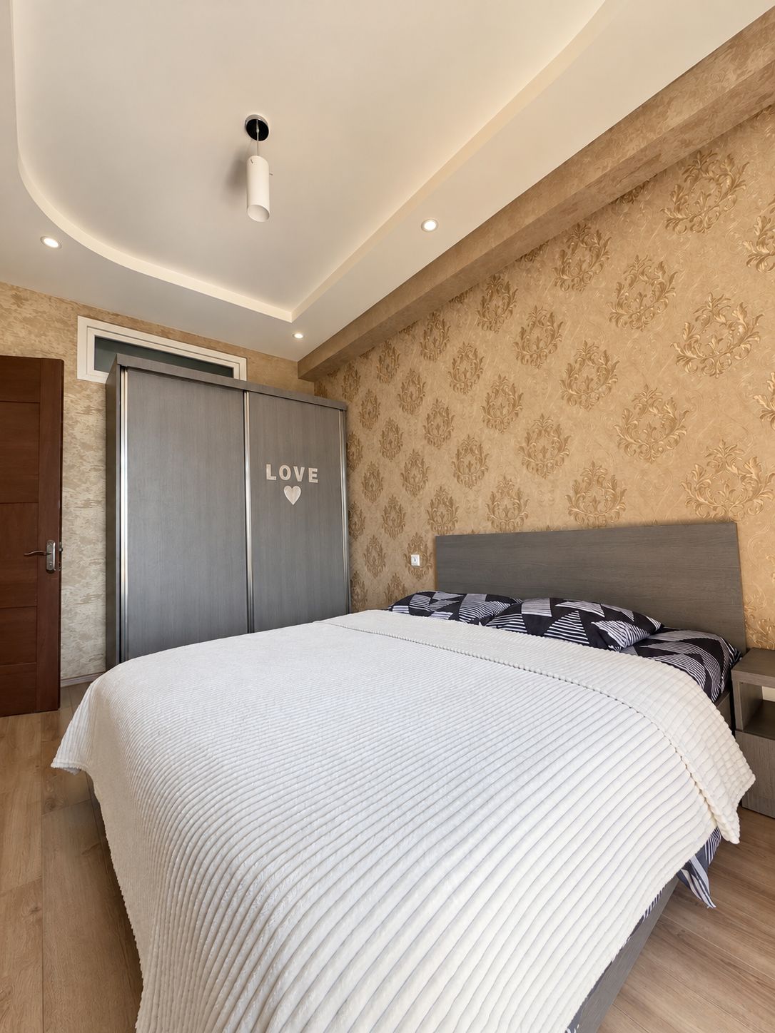 A bedroom with a bed, a wardrobe, and a nightstand.