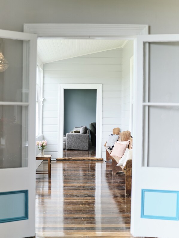 An open doorway leading to a living room with a grey sofa, a coffee table, and a wooden bench.