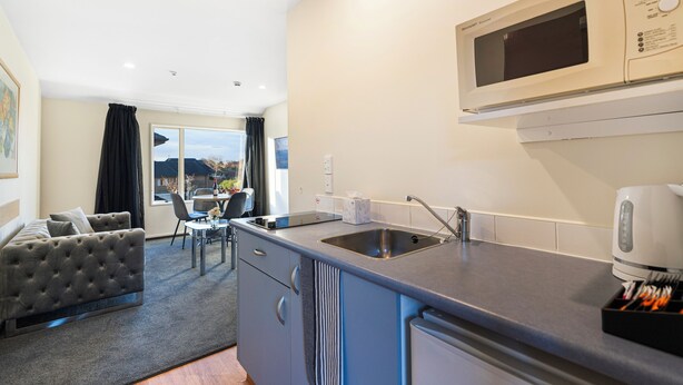 A compact kitchen with a built-in microwave, a sink, and a coffee maker. - Daffodil Motel (Christchurch)