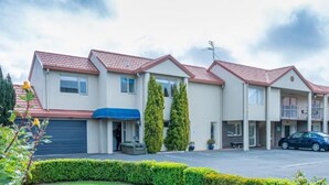 A row of two-story buildings with a parking lot in front. - Daffodil Motel (Christchurch)