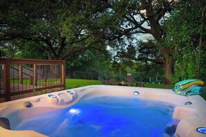 Un bain à remous avec une terrasse en bois et une clôture, situé dans un jardin.
