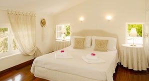 Relax in a serene space with a large bed, two bedside tables, and a window overlooking lush greenery.
