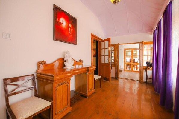 A room with wooden furniture, a painting, and a view through an open door. - Glen View Heritage Homestay (Shimla)