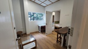 Ein gemütlicher Raum mit Holzboden, einem kleinen Tisch, einem Schreibtisch und einem Bett.