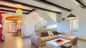 A modern living room with a sofa, coffee table, and hanging light fixtures. - Cozy home in Porec with sauna (Porec)