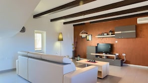 A modern living room with a sofa, TV, and a wooden accent wall. - Cozy home in Porec with sauna (Porec)