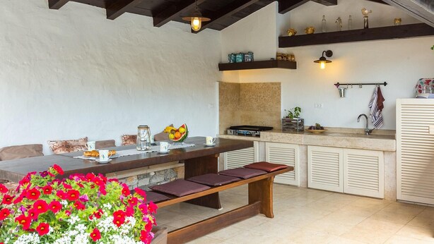 A cozy kitchen with a wooden table, bench, and a variety of kitchen items. - Cozy home in Porec with sauna (Porec)