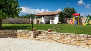 A stone wall, a barbecue area, and a children's play structure. - Cozy home in Porec with sauna (Porec)