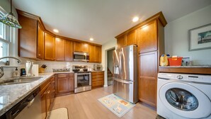 A modern kitchen with wooden cabinets, stainless steel appliances, and a built-in washing machine. - Cozy Ripley Apartment - 21 Mi to Downtown Erie! (Ripley)