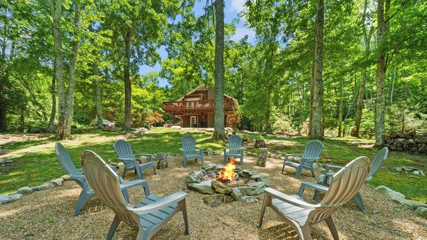 A lodge with a fire pit surrounded by Adirondack chairs, set in a wooded area with a large house in the background. - Four Bear Falls - Walk to Downtown Banner Elk - Fire Pit - Fenced in Pet Friendly (Banner Elk)