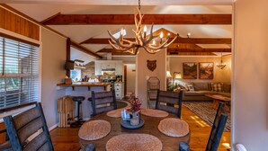 A dining area with a round wooden table, woven placemats, and a chandelier. - Four Bear Falls - Walk to Downtown Banner Elk - Fire Pit - Fenced in Pet Friendly (Banner Elk)