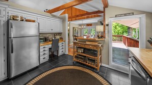 A kitchen with a stainless steel refrigerator, wooden cabinets, a wooden dining table, and a view of a deck. - Four Bear Falls - Walk to Downtown Banner Elk - Fire Pit - Fenced in Pet Friendly (Banner Elk)