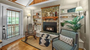 A cozy living room with a fireplace, wooden beams, a stone wall, and a bookshelf. - Four Bear Falls - Walk to Downtown Banner Elk - Fire Pit - Fenced in Pet Friendly (Banner Elk)