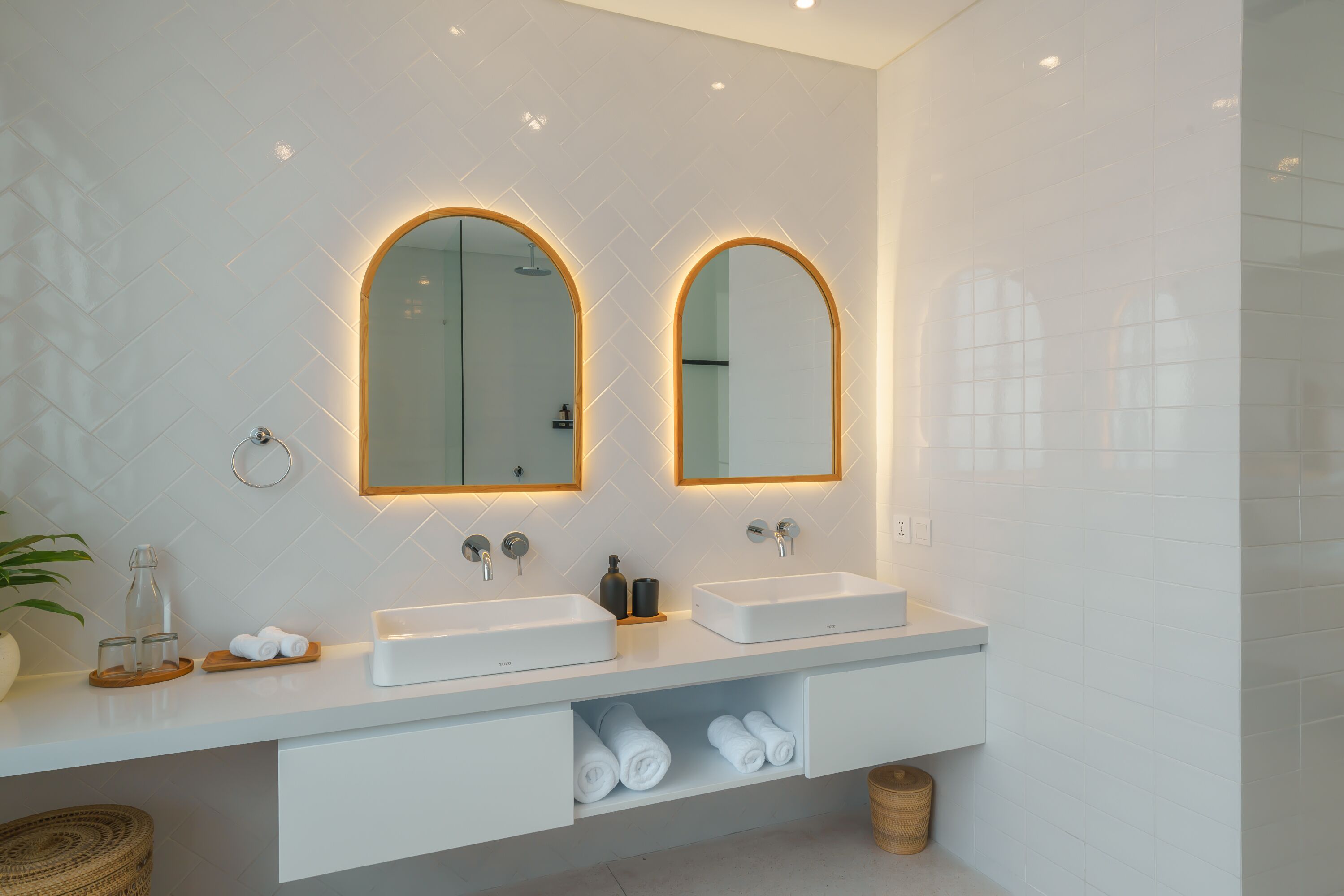 A modern bathroom with two sinks, a mirror, and a towel rack.