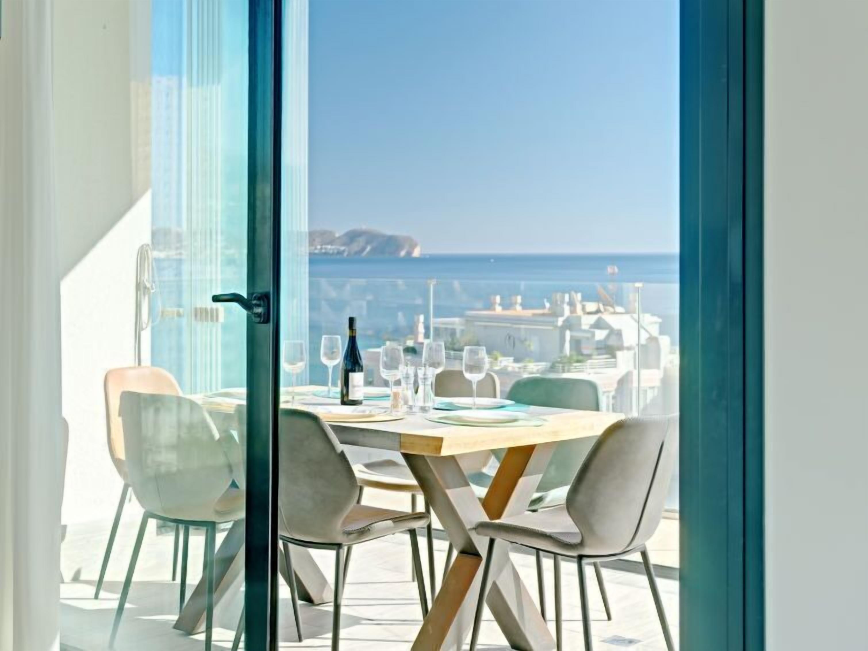 A dining area with a table set for four, overlooking a coastal view.
