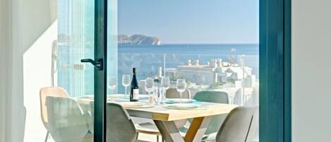 A dining area with a table set for four, overlooking a coastal view.