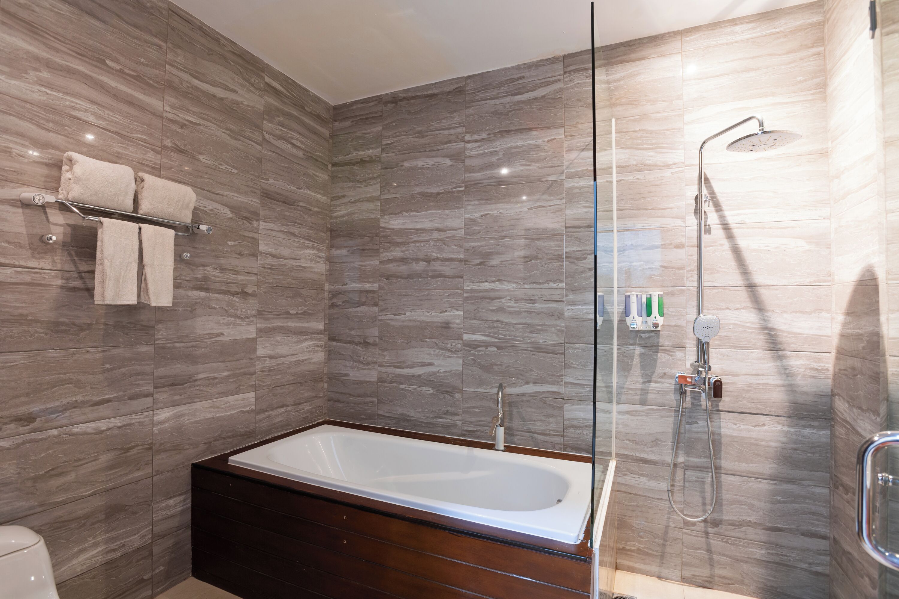 Une salle de bain moderne avec une baignoire sur pieds, une douche à parois de verre et un mur recouvert de carreaux de marbre.