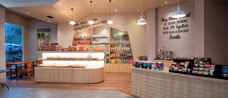 A bakery with a display counter, shelves with baked goods, and a wall with inspirational quotes.