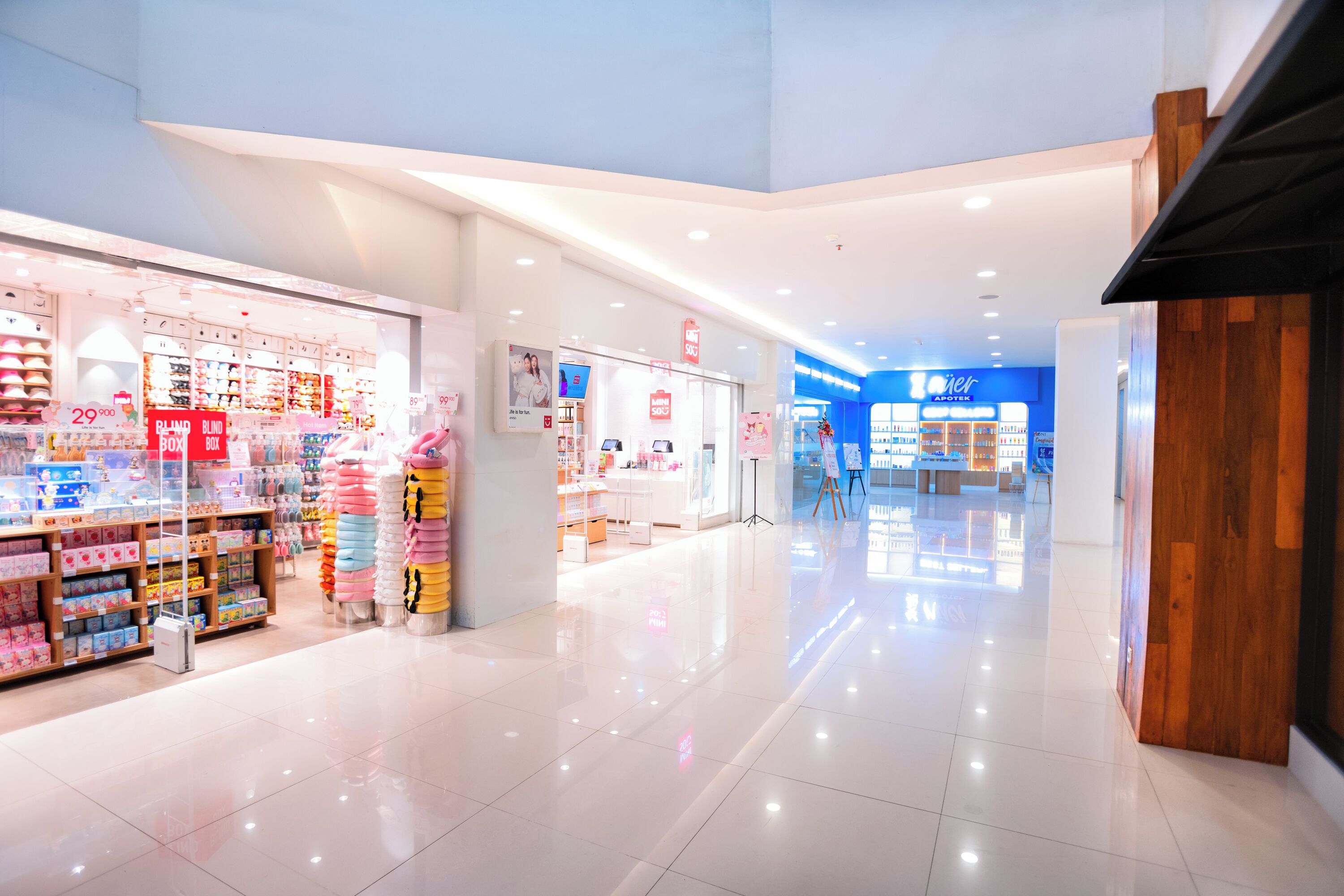 Un grande centro commerciale luminoso e spazioso, con numerosi negozi, tra cui un negozio di cosmetici ben visibile e un negozio di mobili.