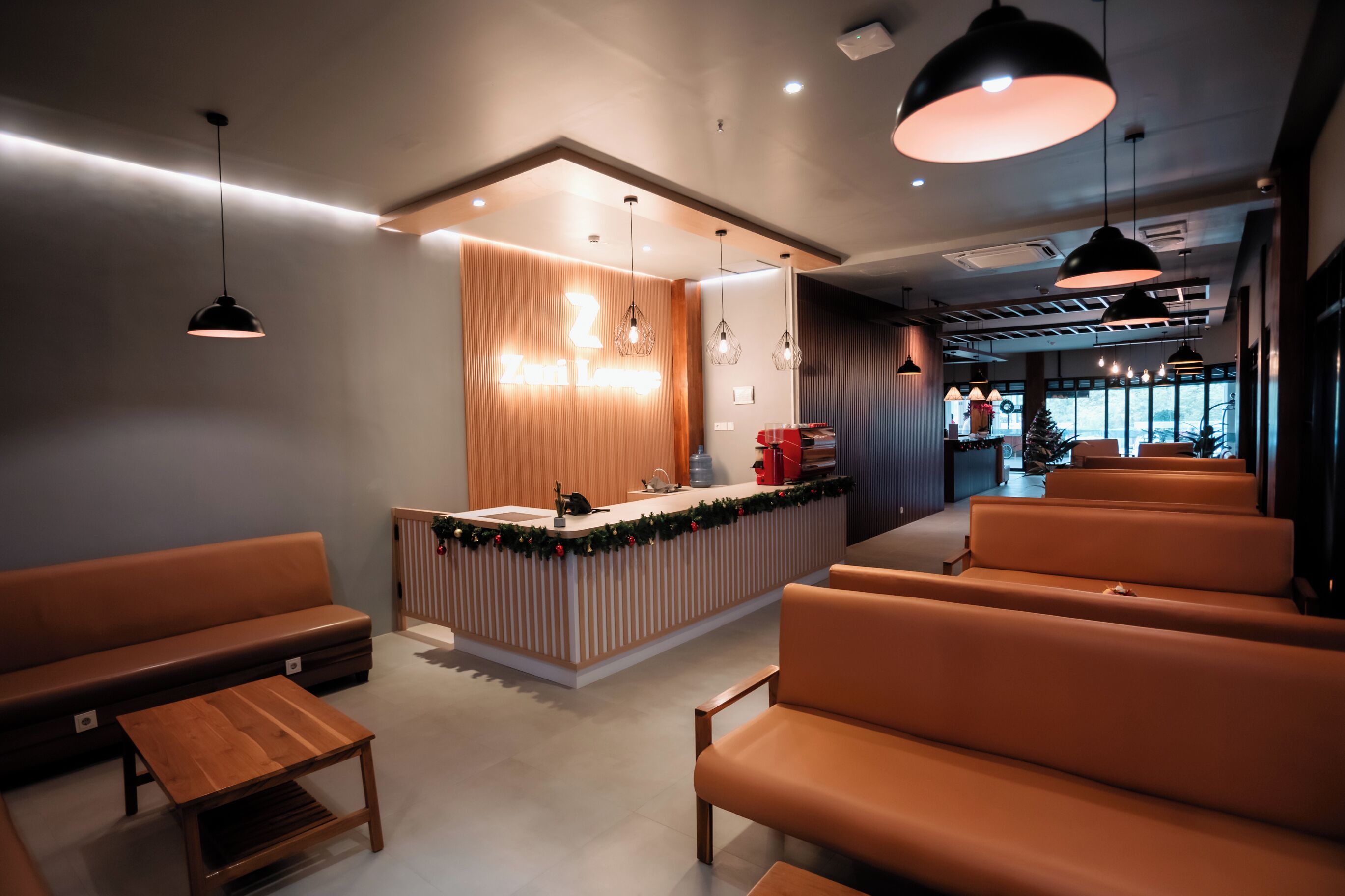 A modern reception area with a wooden counter, seating area, and pendant lighting.