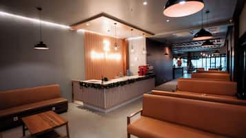 A modern reception area with a wooden counter, seating area, and pendant lighting.