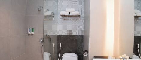 Un baño moderno con cabina de ducha de vidrio, inodoro con barra para toallas y lavabo con espejo.