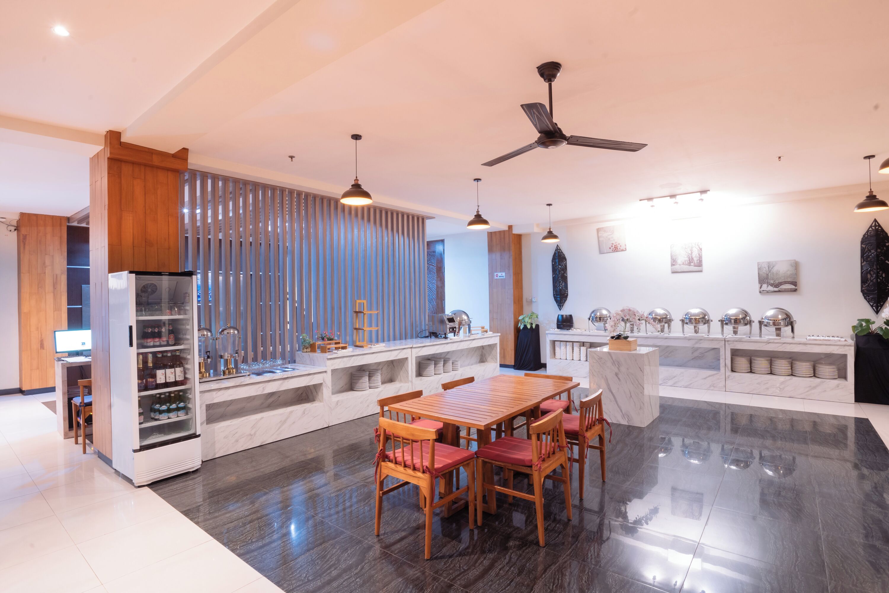 A modern kitchen with a dining area, wooden cabinets, a marble countertop, and a ceiling fan.