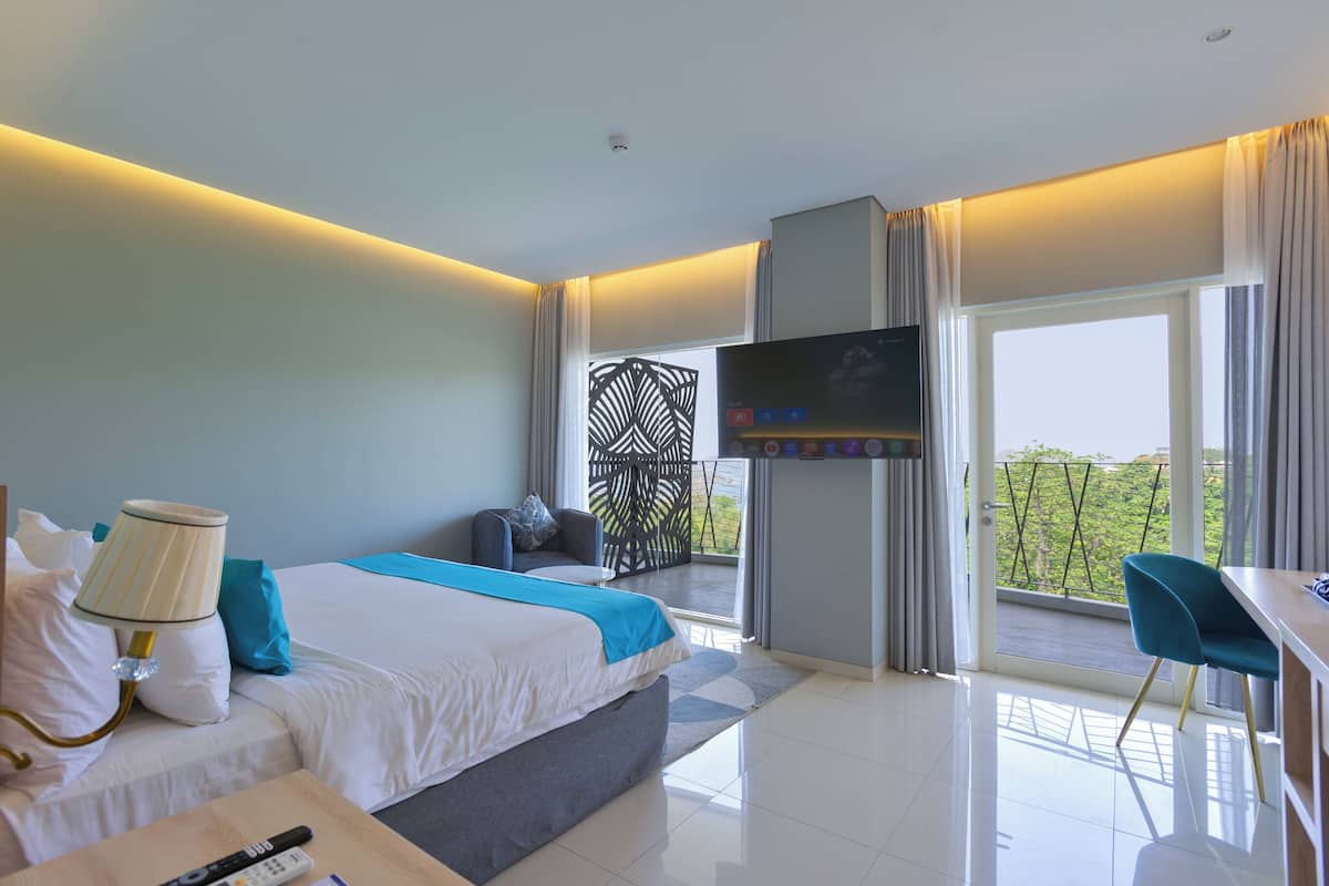 A modern hotel room with a bed, a desk, a TV, and a balcony with a view.