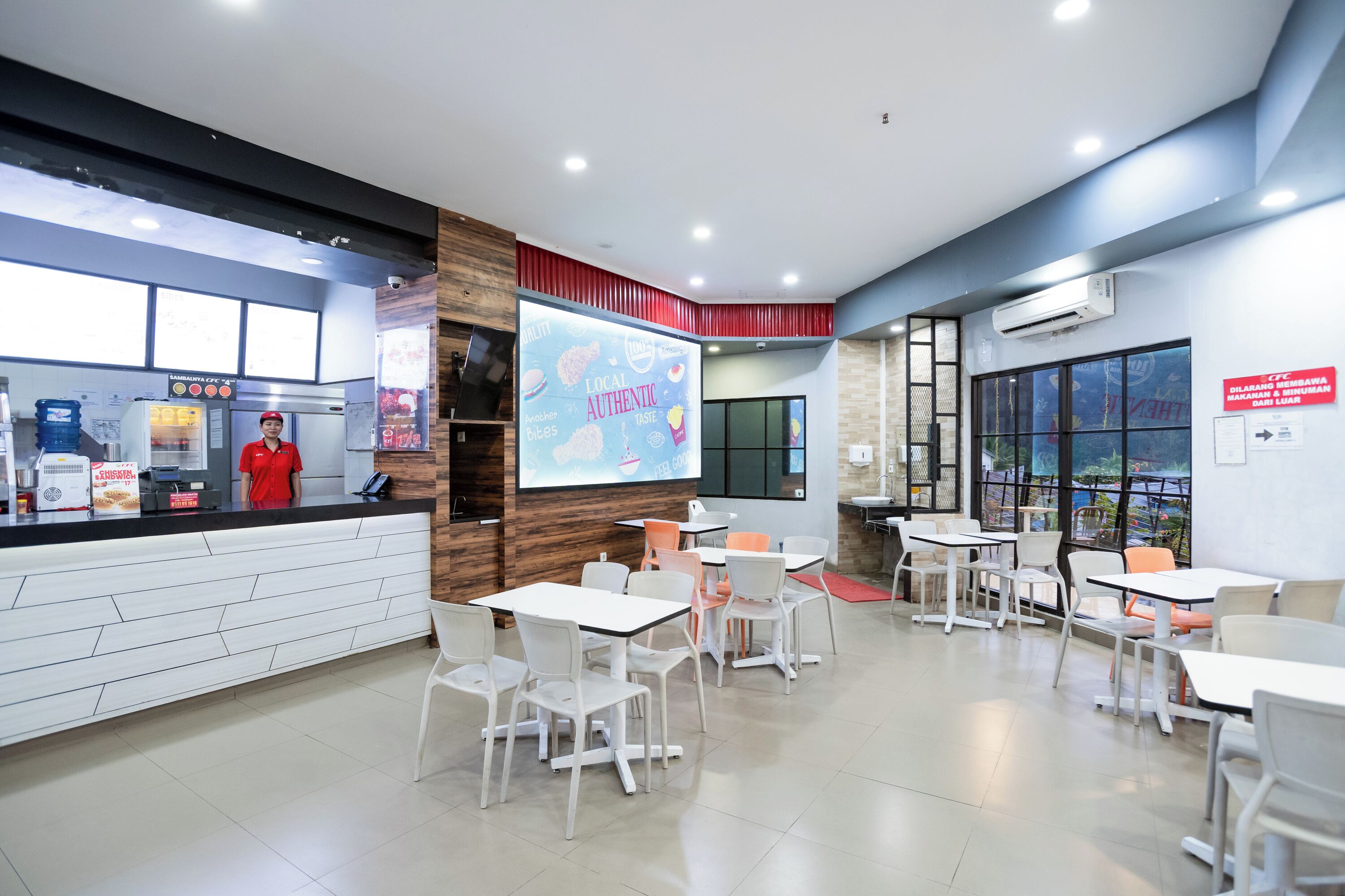 A modern cafe with a counter, seating area, and a projection screen displaying 'Local Authentic'.