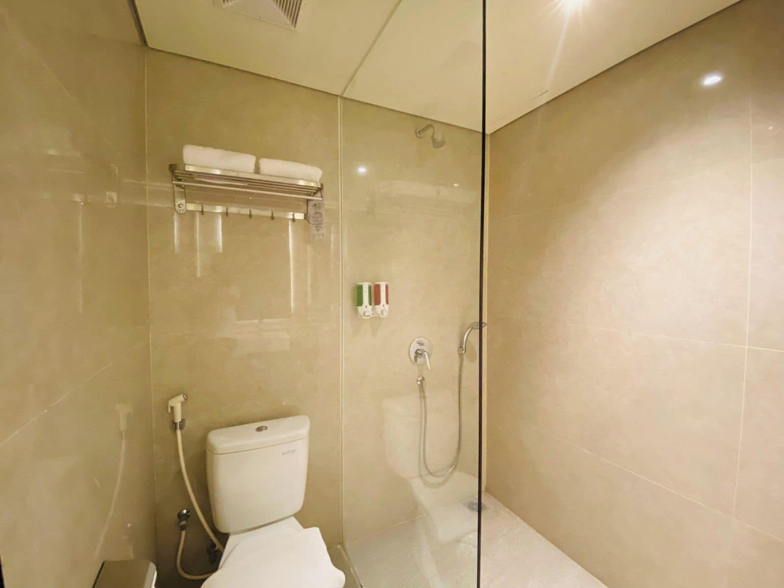 Un baño moderno con cabina de ducha de vidrio, inodoro y toallero.
