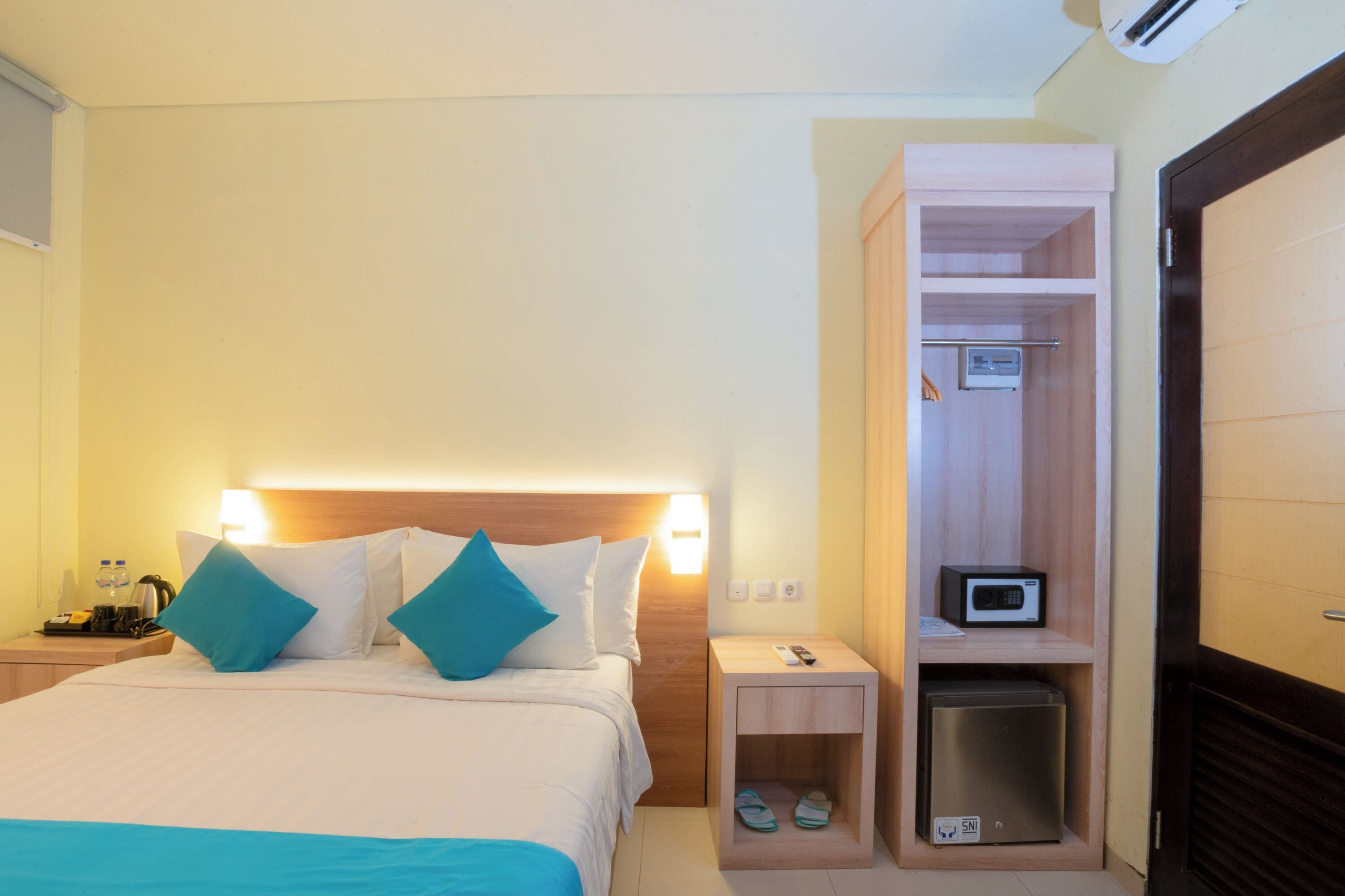 A hotel room with a bed, bedside table, and a built-in closet with a microwave.