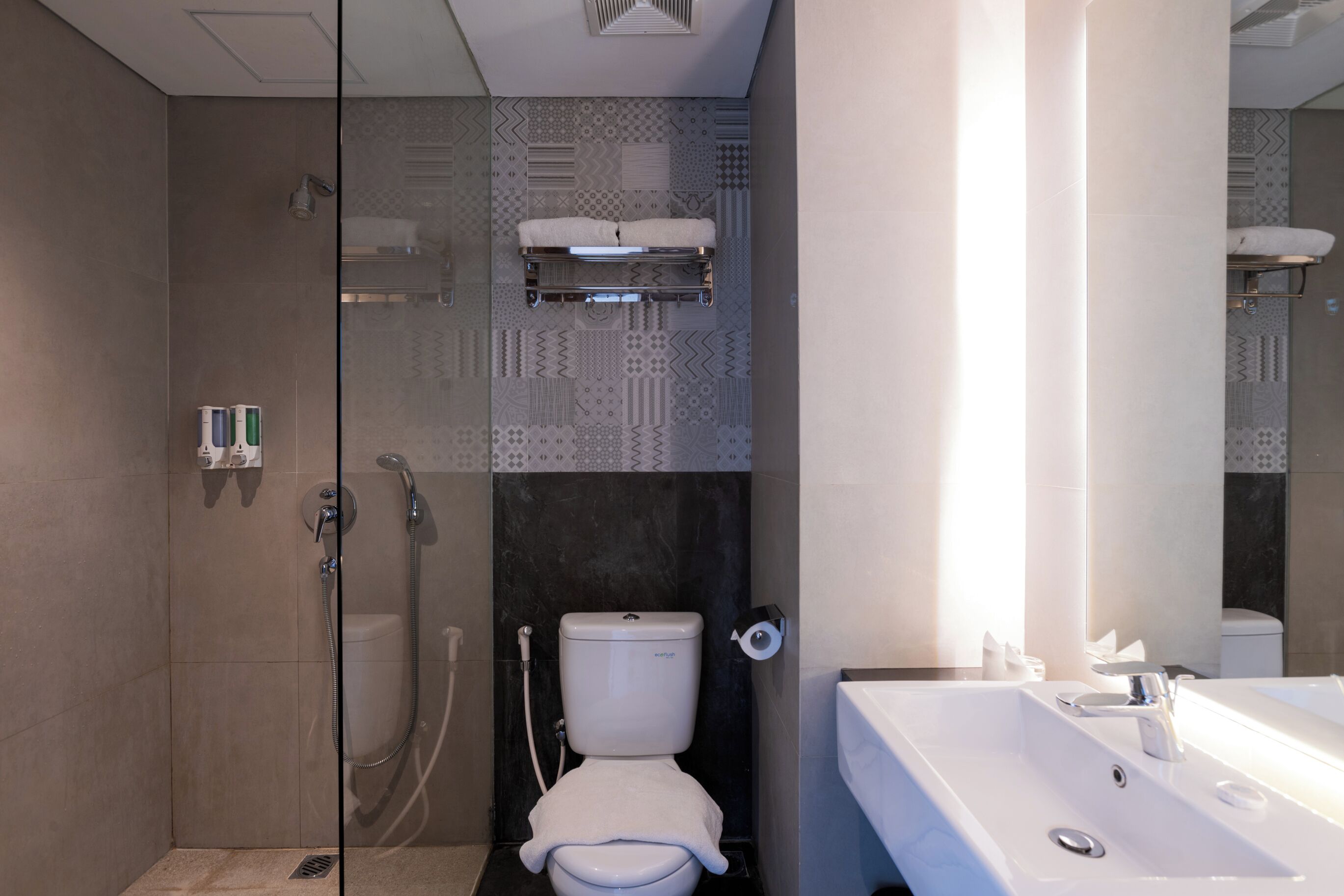 Une salle de bain moderne avec une douche à parois de verre, des toilettes et un lavabo avec un miroir.