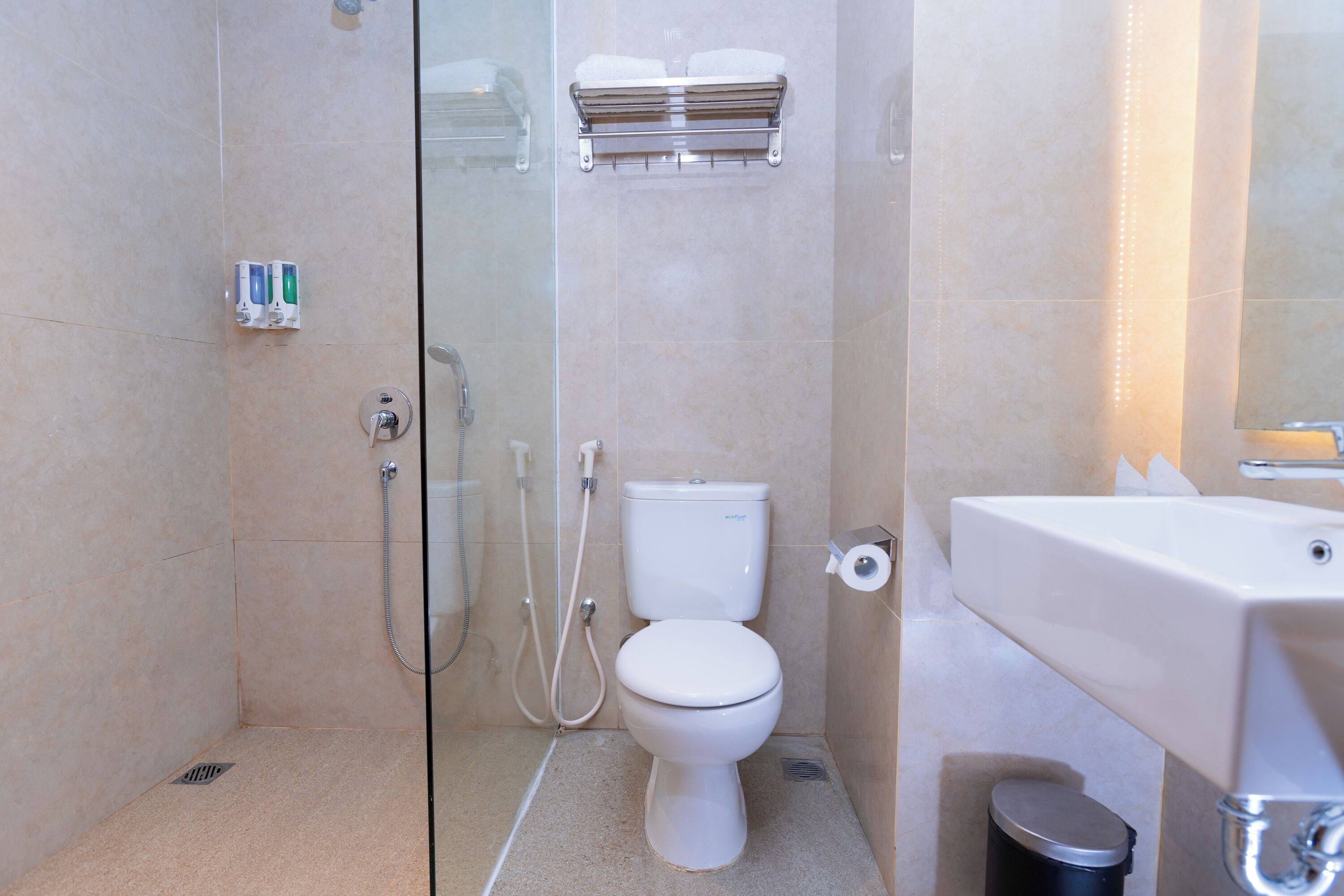 A modern bathroom with a glass shower enclosure, a toilet, a sink, and a trash can.
