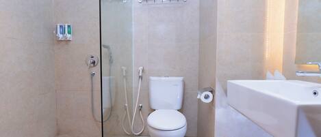 A modern bathroom with a glass shower enclosure, a toilet, a sink, and a trash can.