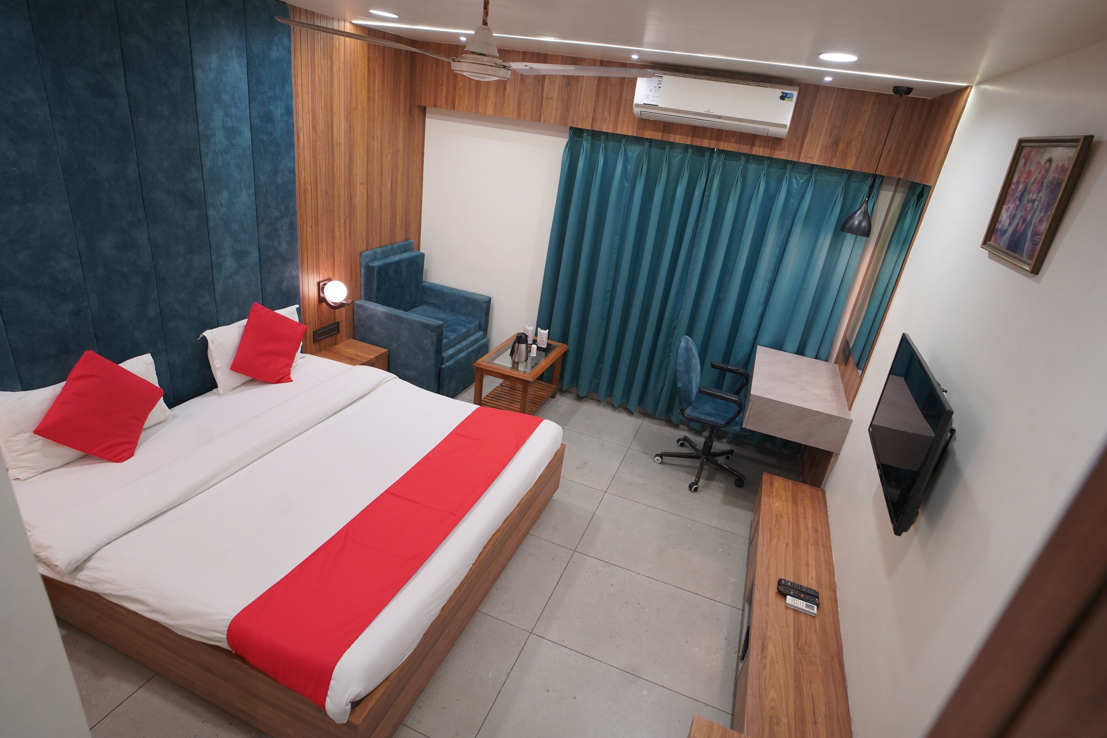 A hotel room with a large bed, a desk, a chair, and a TV.