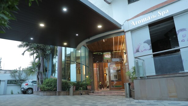 A spa entrance with a modern design, a car parked outside, and potted plants. - Hotel Gokul (Gandhidham)