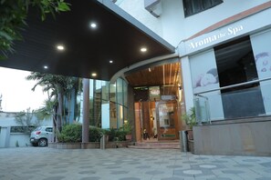 A spa entrance with a modern design, a car parked outside, and potted plants. - Hotel Gokul (Gandhidham)