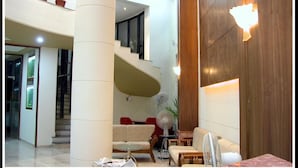 A spacious lobby with a spiral staircase, seating area, and a fan. - Hotel Gokul (Gandhidham)