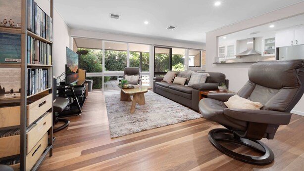 Una sala de estar moderna con un sofá, sillones, una mesa de centro y una estantería.