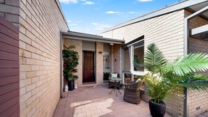 Edificio de ladrillo con un patio cubierto que incluye mobiliario exterior y plantas en macetas.