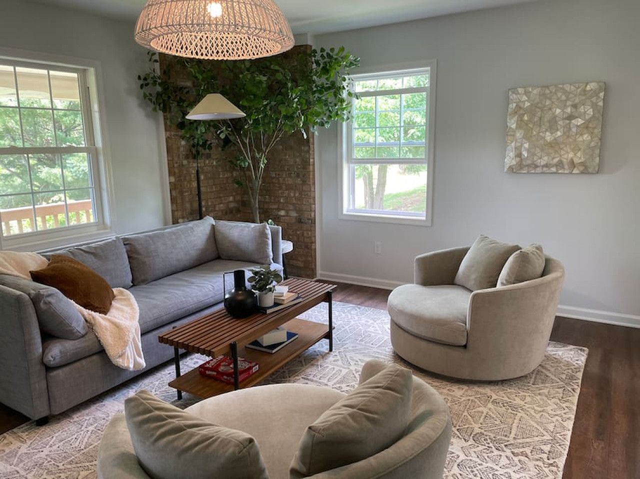 A living room with a sectional sofa, a round armchair, a coffee table, and a large window.