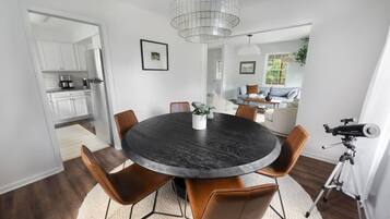 A dining area with a round table, chairs, and a telescope.