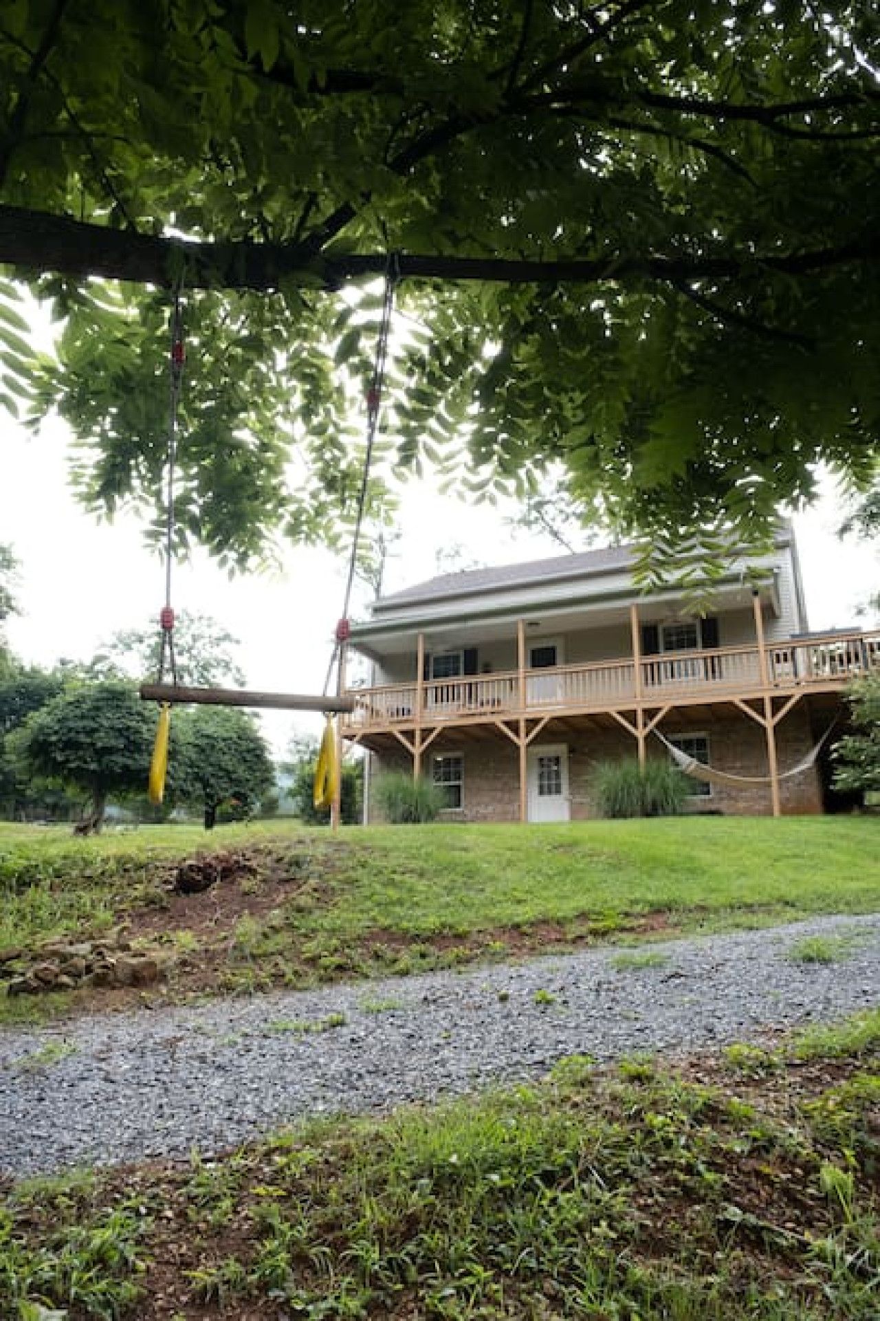Une maison à deux étages dotée d’un balcon, entourée de verdure.